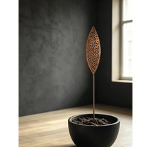 Pic de jardin en métal en forme de feuille avec découpes florales dans un pot noir, dans un environnement moderne et minimaliste.