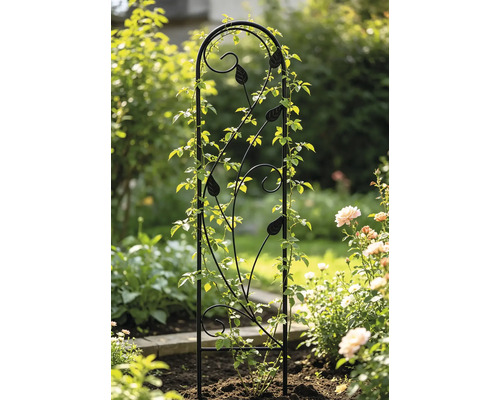 Schwarze Rankhilfe aus Metall mit dekorativen Blättern und Schnörkeln für Kletterpflanzen in einem Gartenbeet.