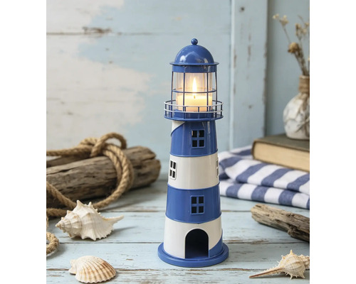 Porte-bougie chauffe-plat en forme de phare marin en métal, rayures bleues et blanches, avec bougie allumée et décorations maritimes.
