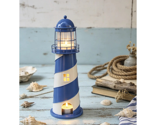 Lanterne phare maritime en métal à rayures bleues et blanches, décorée dans une scène lumineuse avec coquillages, corde et bois flotté sur bois.