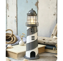 Porte-bougie chauffe-plat décoratif en forme de phare avec motif en spirale et bougie allumée dans une scène maritime avec corde, livres et coquillages.