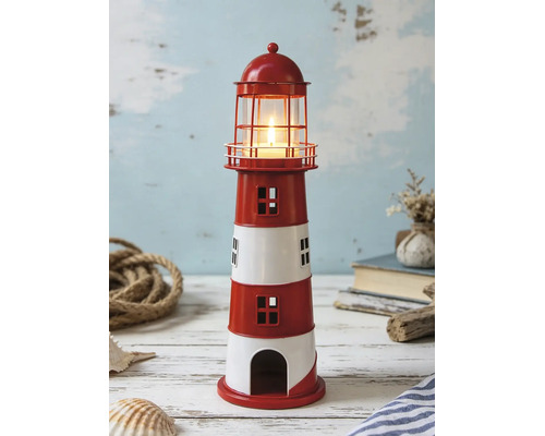 Photophore en métal en forme de phare à rayures avec bougie allumée dans un décor maritime avec corde et coquillages.