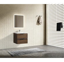 Meuble de salle de bain suspendu aspect bois avec lavabo blanc, robinetterie et miroir mural rétroéclairé dans une pièce au style épuré.