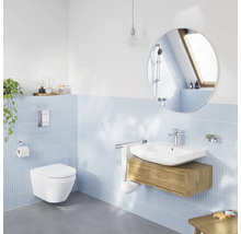 Salle de bain moderne et lumineuse avec WC suspendu, lavabo blanc sur meuble sous-vasque en bois, miroir rond et carrelage mural bleu clair.