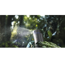 Brumisateur automatique avec WIPER Logo projetant une fine brume d'eau sur des feuilles vertes dans un jardin.