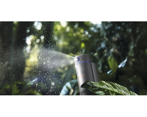 Brumisateur automatique avec WIPER Logo projetant une fine brume d'eau sur des feuilles vertes dans un jardin.