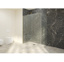 Salle de bains moderne avec cabine de douche en verre et profilés dorés, carrelage mural effet marbre foncé et WC suspendu blanc.