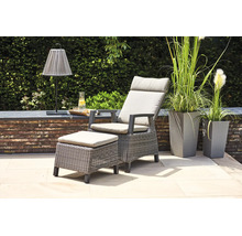 Fauteuil de jardin en polyrotin avec pouf assorti et coussins clairs sur une terrasse moderne avec de hauts bacs à fleurs.