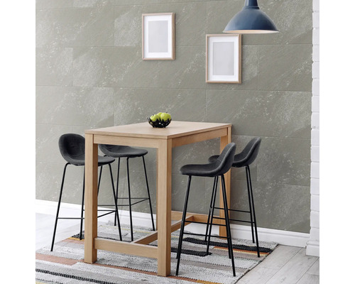 Table de bar moderne en bois avec quatre tabourets devant des panneaux muraux aspect pierre, sur un tapis à motifs sous une suspension.