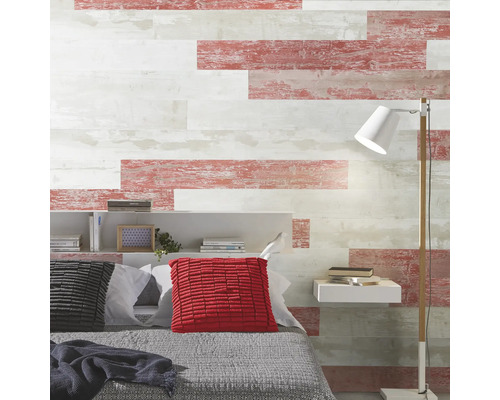 Mur de chambre avec des panneaux horizontaux aspect bois vieilli en blanc et rouge, lit avec coussins, étagère et lampadaire.