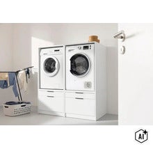 Zwei weiße Waschmaschinenschränke nebeneinander mit Waschmaschine und Trockner, darunter jeweils eine Schublade, in einem hellen Waschraum. (Image AI modified or generated)