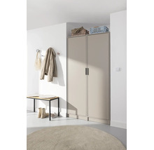 Entrée moderne avec armoire beige à deux portes, banc en bois, patères sur mur blanc et tapis rond.