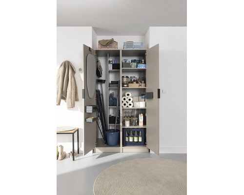 Armoire ménagère multi-usage ouverte à deux portes, organisée avec table à repasser, séchoir à linge, produits de nettoyage et provisions.