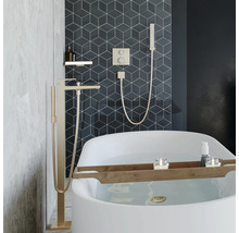 Salle de bain moderne avec baignoire îlot, mitigeur de baignoire sur pied et robinetterie encastrée avec douchette devant des carreaux géométriques.