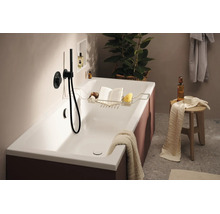 Baignoire moderne avec tablette, livre, éponge et mitigeur. Ambiance de salle de bain élégante avec serviette et tabouret de rangement.