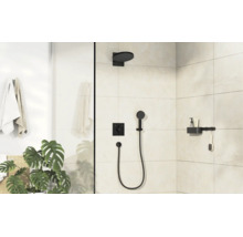 Cabine de douche moderne avec robinetterie encastrée noire, pomme de douche, douchette et étagère sur mur carrelé clair dans une salle de bain.