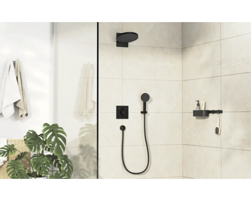 Cabine de douche moderne avec robinetterie encastrée noire, pomme de douche, douchette et étagère sur mur carrelé clair dans une salle de bain.