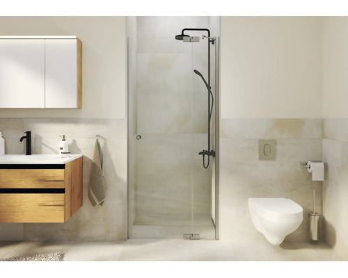 Salle de bains moderne avec douche en verre, meuble vasque en bois, toilettes suspendues et robinetterie de douche sombre dans une pièce carrelée.