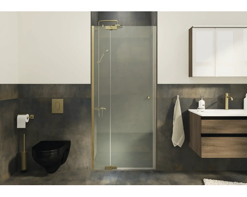 Paroi de douche moderne avec porte battante et profilés couleur laiton dans une salle de bain élégante avec carrelage sombre.