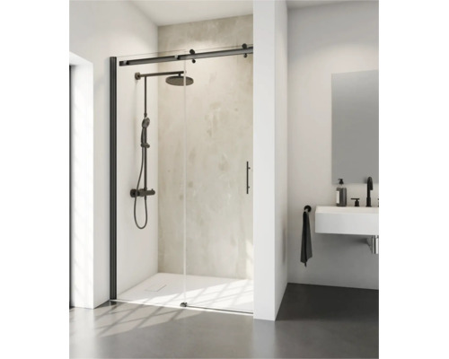 Cabine de douche moderne avec porte coulissante et quincaillerie noire, installée dans une salle de bain lumineuse avec douche pluie et lavabo.