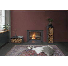 Cheminée moderne avec étagères à bois dans un salon avec un grand tapis et des coussins devant un feu allumé.
