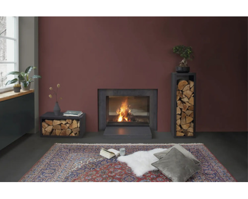 Cheminée moderne avec étagères à bois dans un salon avec un grand tapis et des coussins devant un feu allumé.