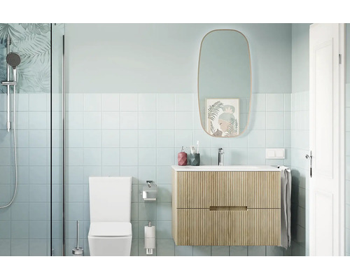 Salle de bain moderne avec meuble sous vasque suspendu à structure rainurée, miroir ovale, toilettes et douche avec paroi vitrée.