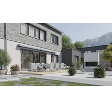 Terrasse moderne avec coin repas devant une maison en briques avec store et cheminée extérieure dans un jardin soigné avec vue sur la montagne.