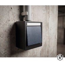 Interrupteur en saillie dans un boîtier robuste monté sur un mur en béton avec conduit de câbles. (Image AI modified or generated)