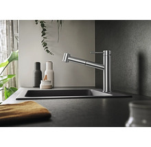 Mitigeur de cuisine moderne avec douchette extractible dans une cuisine élégante avec évier et éléments décoratifs.