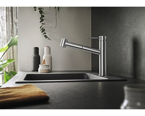 Mitigeur de cuisine moderne avec douchette extractible dans une cuisine élégante avec évier et éléments décoratifs.