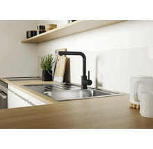 Évier de cuisine moderne en acier inoxydable avec robinet mitigeur noir sur un plan de travail aspect bois dans une cuisine lumineuse.