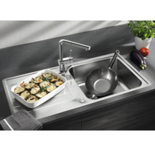 Évier de cuisine moderne en acier inoxydable avec robinet intégré, égouttoir, un plat à four et une poêle dans une cuisine fonctionnelle.