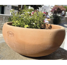 Runde Pflanzschale aus Terrakotta mit handgefertigtem Terraneo Logo, bepflanzt mit Blumen, geeignet für Garten und Terrasse.