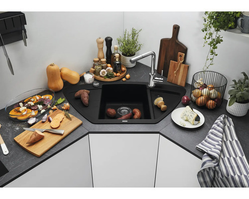 Évier d angle avec robinetterie dans une cuisine moderne avec plan de travail aspect pierre, entouré d ustensiles de cuisine et d aliments.
