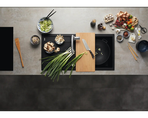 Vue de dessus d'un évier moderne en composite avec planche à découper intégrée et mitigeur de cuisine dans un plan de travail préparé.