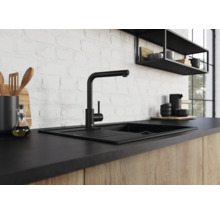 Mitigeur de cuisine noir moderne avec évier devant un mur en briques blanches dans une cuisine avec façades en bois.