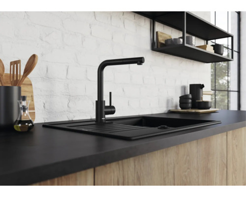 Mitigeur de cuisine noir moderne avec évier devant un mur en briques blanches dans une cuisine avec façades en bois.