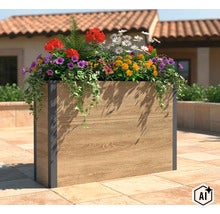 Rechteckiger Pflanzkübel mit Holzoptik und dunklen Metallecken, bepflanzt mit Blumen auf einer Terrasse vor einem Haus. (Image AI modified or generated)
