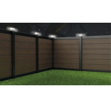 WPC Sichtschutzzaun mit integrierter LED Beleuchtung auf den Pfosten in einem Garten bei Nacht.