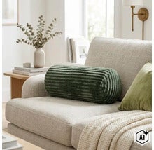 Zylindrisches Dekokissen mit gerippter Struktur auf einem modernen Sofa in einem hellen Wohnzimmer. (Image AI modified or generated)