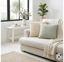 Helles Wohnzimmer mit Sofa, strukturierten Zierkissen, Überwurfdecke, Beistelltisch mit Blumenvase und Zimmerpflanze in moderner Einrichtung. (Image AI modified or generated)