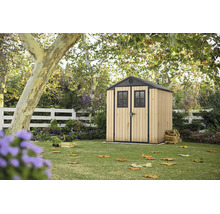 Abri de jardin en bois et métal dans un jardin avec pelouse sous des arbres.