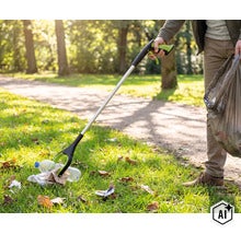 Une personne utilise une pince à déchets dans un parc pour ramasser une bouteille en plastique et la placer dans un sac poubelle. (Image AI modified or generated)