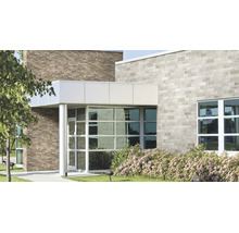 Façade d'un bâtiment commercial moderne avec des briques claires et sombres, de grandes baies vitrées et une entrée couverte.