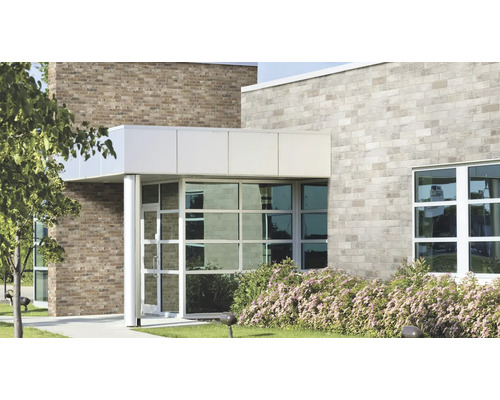 Façade d'un bâtiment commercial moderne avec des briques claires et sombres, de grandes baies vitrées et une entrée couverte.