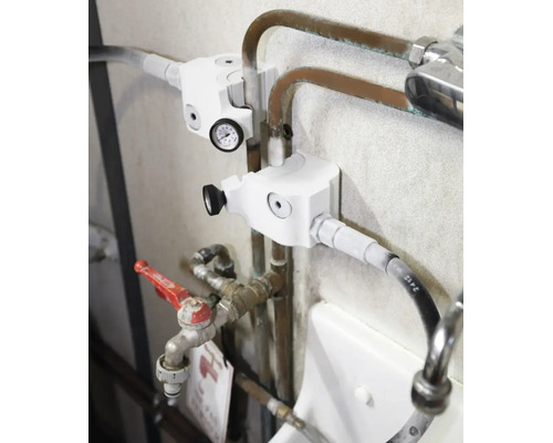 Heizungsarmatur mit Thermometer montiert an Kupferrohren im Heizungskeller.