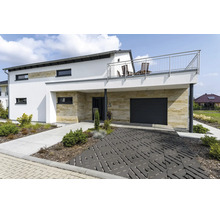 Maison individuelle moderne avec revêtement en pierre naturelle, garage, balcon avec garde-corps en acier inoxydable et allée pavée décorative.