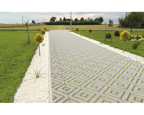 Allée pavée avec des dalles de gazon carrées dans un jardin avec pelouse et arbustes ornementaux.