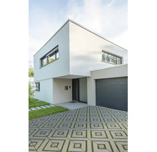 Maison moderne à deux étages avec toit plat, garage intégré et allée pavée avec joints en gazon.